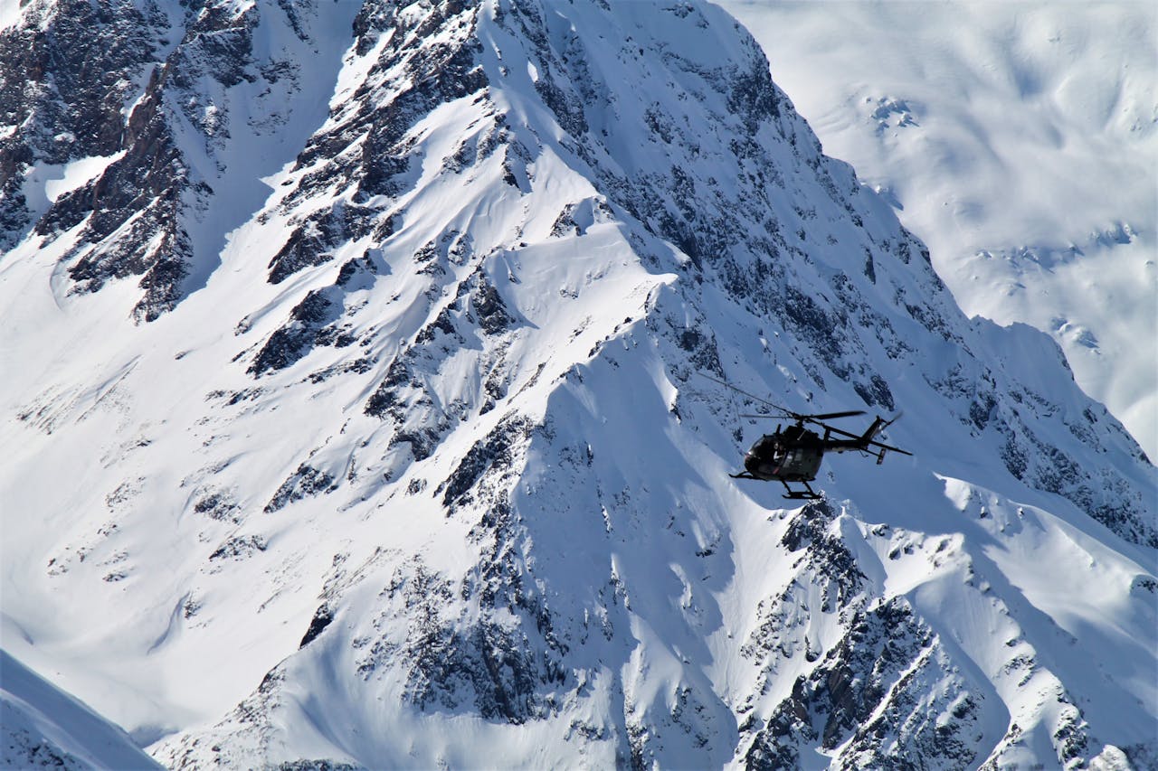 services-07 A helicopter soars over the majestic snow-covered peaks of Dombay in winter.